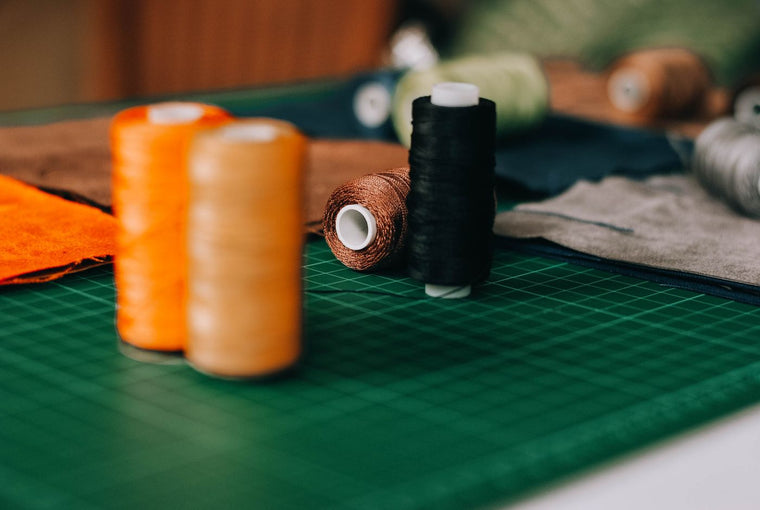 Colourful sewing thread spools arranged beside fabric and sewing tools on a craft table