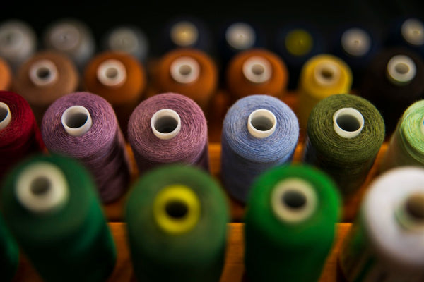 Rows of assorted coloured sewing thread spools for choosing a shade to match fabric