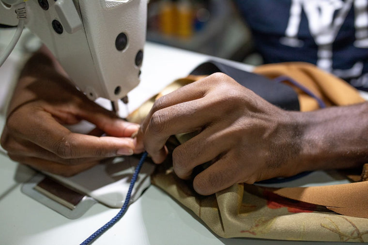 Hands guiding thread through the needle area of a sewing machine