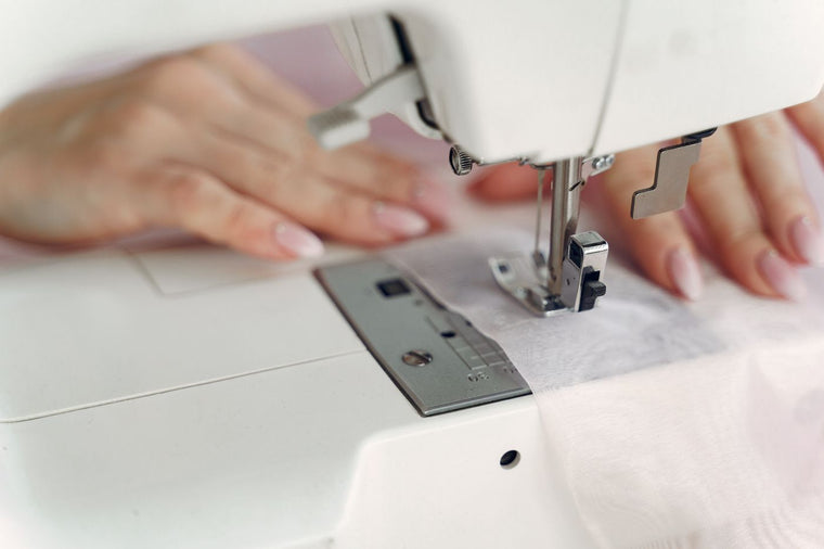 A person guiding fabric through a domestic sewing machine